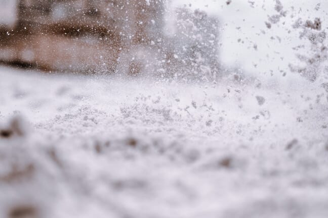 Low-angle close-up of snow falling quickly on the road.