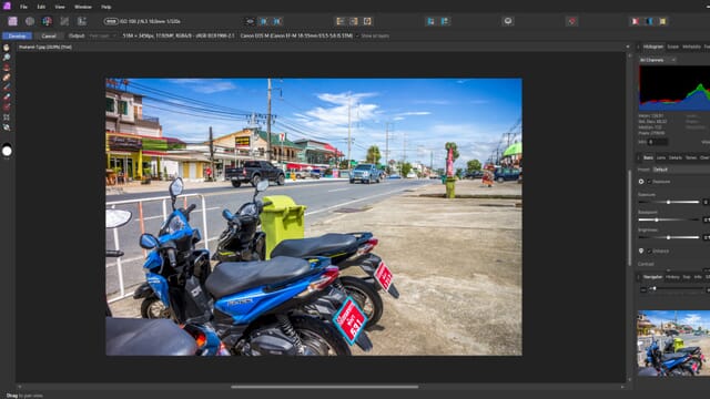 Affinity Photo 2 editing interface with an image of blue and green motorcycles by a road with colorful shops.
