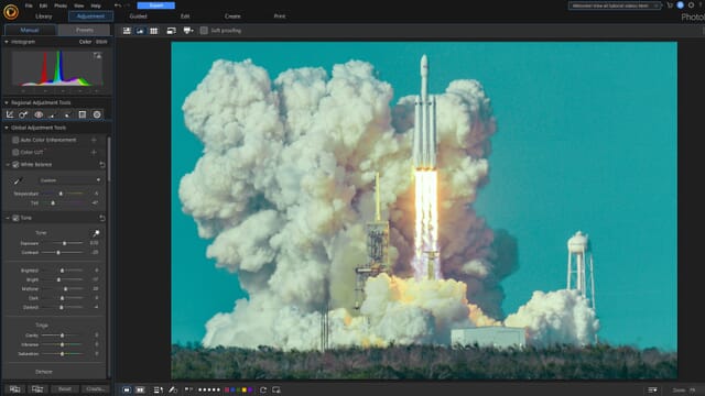 The PhotoDirector 365 editing interface with sliders on the left and an image of a launching rocket against a teal sky on the right.