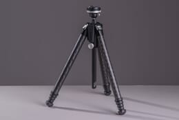 The Benro Theta tripod standing upright on a gray surface with its legs fully compacted.