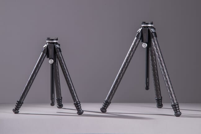 The Theta and the Theta Max tripods fully compacted standing side by side on a gray surface with a gray background.