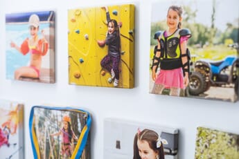 Photo tiles of a young girl doing various activities hung on a white wall.