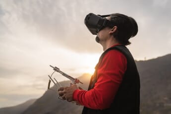Man using FPV goggles to pilot his drone at sunset.