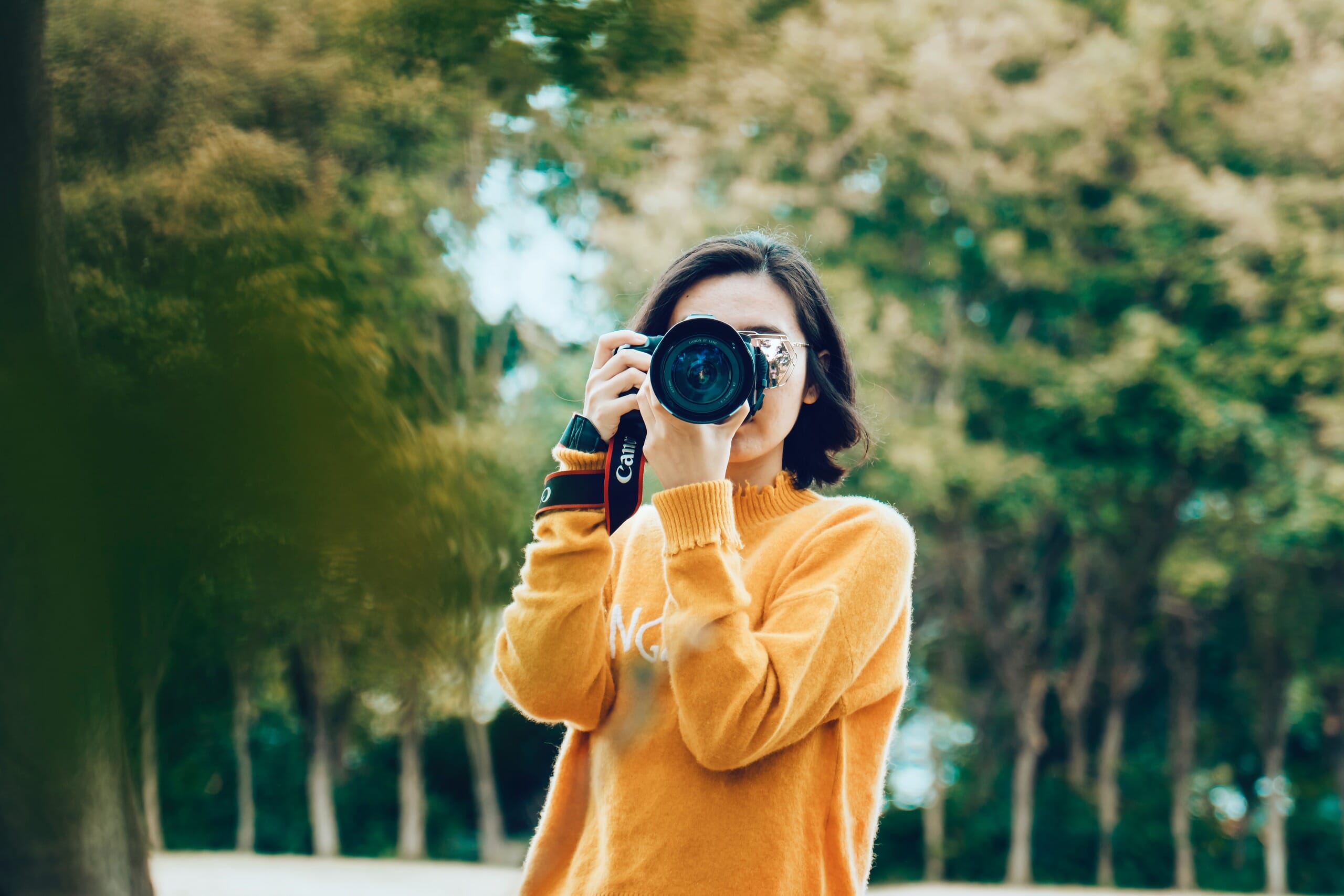 Woman holding a digital camera and looking through the lens finder.