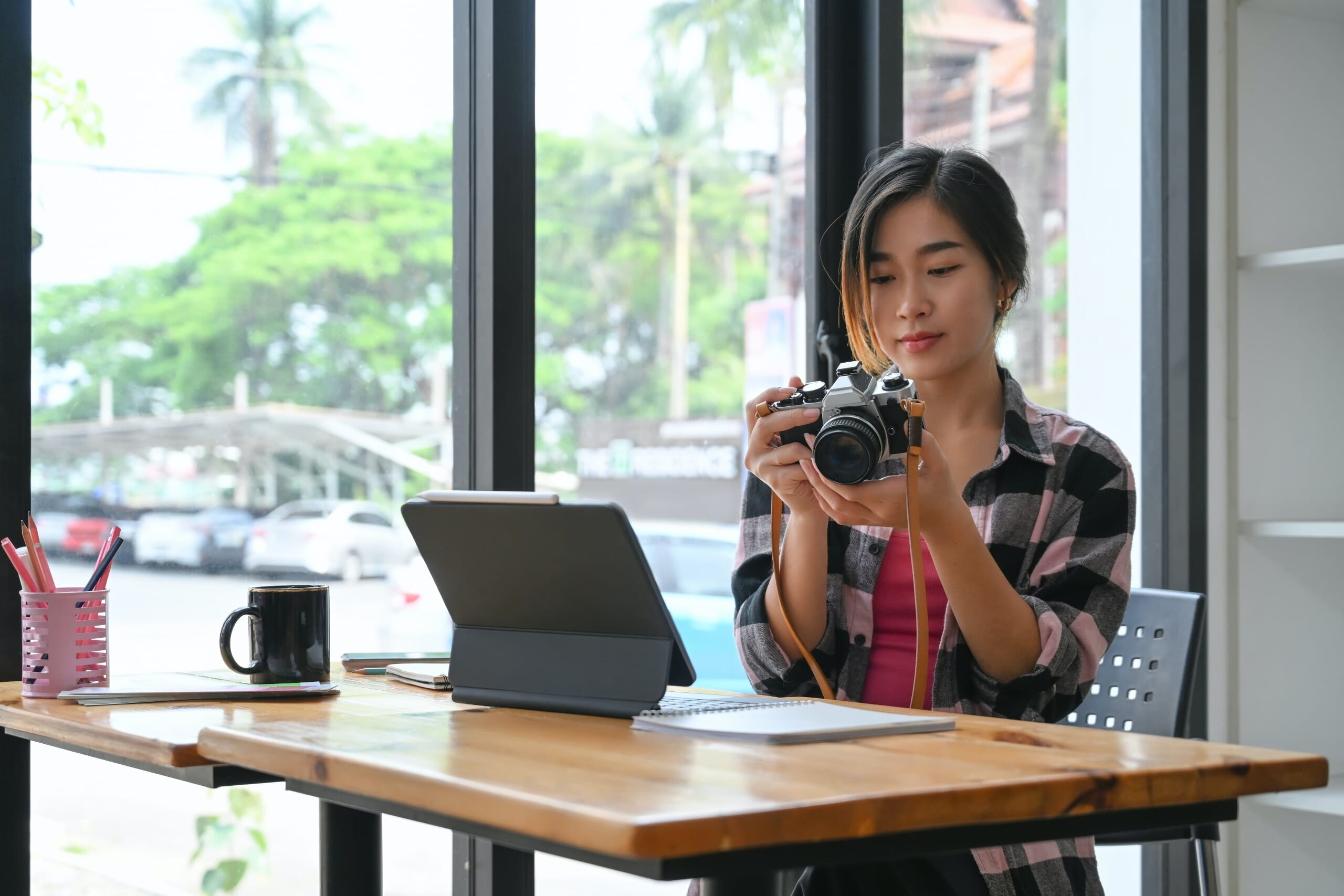 Woman looking at camera display with ipad on desk.