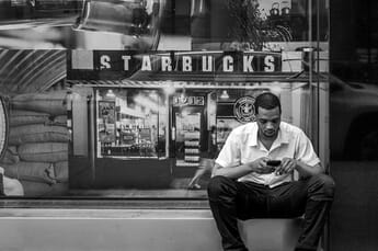 Man sitting outside Starbucks looking at his smartphone.