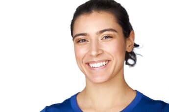 A smiling woman with dark hair tied back, wearing a blue top, against a white background.