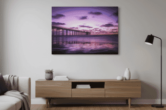 Modern living room with minimalist decor features a striking purple ocean sunset wall art canvas print above a wooden console table, creating a serene coastal vibe.