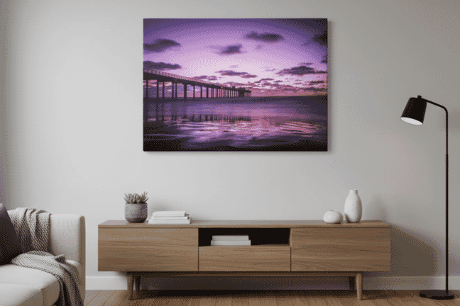 Modern living room with minimalist decor features a striking purple ocean sunset wall art canvas print above a wooden console table, creating a serene coastal vibe.