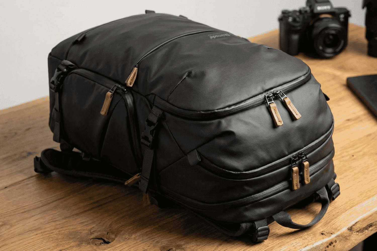 Sleek black camera backpack with multiple compartments and leather zipper pulls, designed for photographers and gear storage on professional shoots.