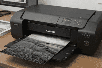 High-quality Canon PRO-310 photo printer producing a detailed black and white landscape print on a modern wooden desk setup.