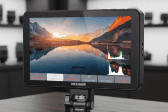 A Neewer camera monitor displays a vibrant mountain landscape with on-screen histogram and focus peaking features in a professional studio setting.
