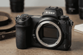 A close-up of the sleek and professional Nikon Z7 II mirrorless camera body displayed on a wooden surface with soft background blur.