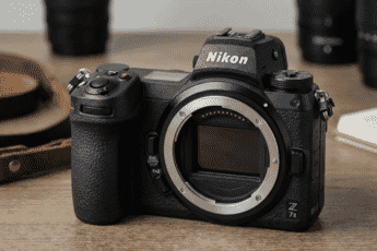 A close-up of the sleek and professional Nikon Z7 II mirrorless camera body displayed on a wooden surface with soft background blur.