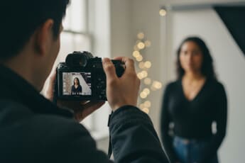 Photographer using aperture priority mode on mirrorless camera during a portrait session in studio