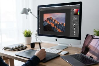 Professional workspace with Adobe Photoshop interface on monitor showing photo editing