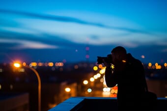Photographer shooting in low light conditions during blue hour in a city