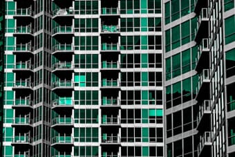 Modern building with repeating geometric patterns in teal glass and balconies