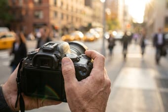 Photographer adjusting camera mode dial to Program Mode on a DSLR camera