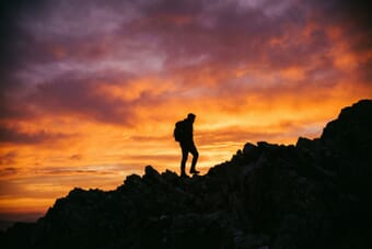 Silhouette of a person against a dramatic sunset sky