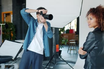 Photographer taking a portrait of a model in a professional studio setup with lighting equipment