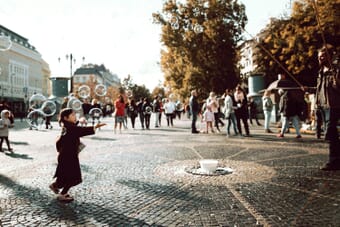 Urban street photography scene with people playing with bubbles in a city street