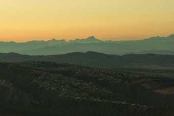 Layered mountain ranges under a golden sunset sky — landscape photography settings guide