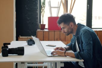 Photographer editing photos on laptop in studio — AI is transforming photography workflows