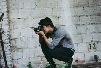Photographer crouching low to capture a creative camera angle