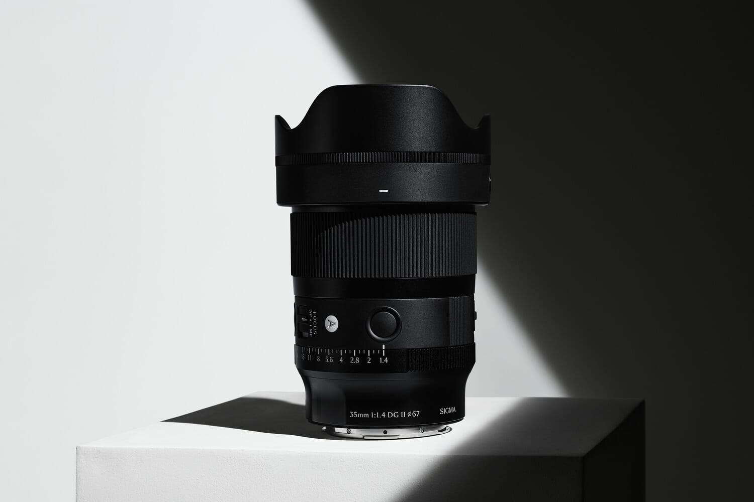 Sigma 35mm f/1.4 DG II Art lens product shot on white pedestal with dramatic lighting