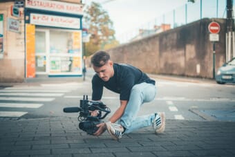 Professional cinema camera operator filming on location, representing the Sony FX6 cinema camera used by indie filmmakers and video professionals
