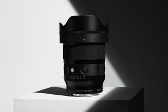 Sigma 35mm F1.4 DG II Art lens on white pedestal with dramatic lighting