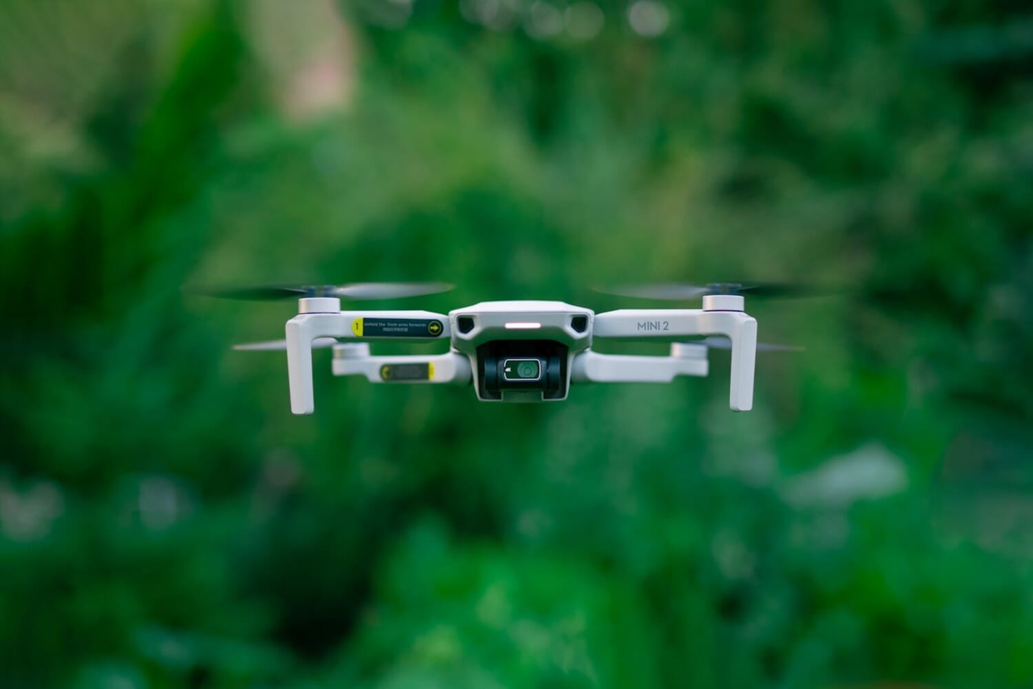 DJI Mini drone hovering in flight against a clear sky