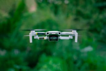 DJI Mini drone hovering in flight against a clear sky