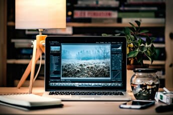 A photographer editing RAW photos on a laptop — Aftershoot now adds a full RAW editor to its culling workflow.