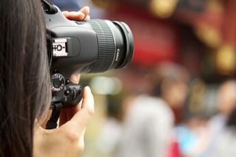 A photographer holding a camera with a telephoto lens up to their eye